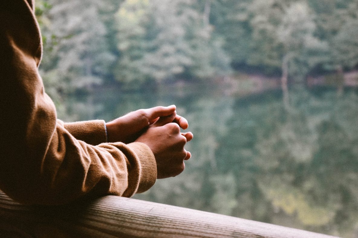Man leaning on railing looking at a lake
