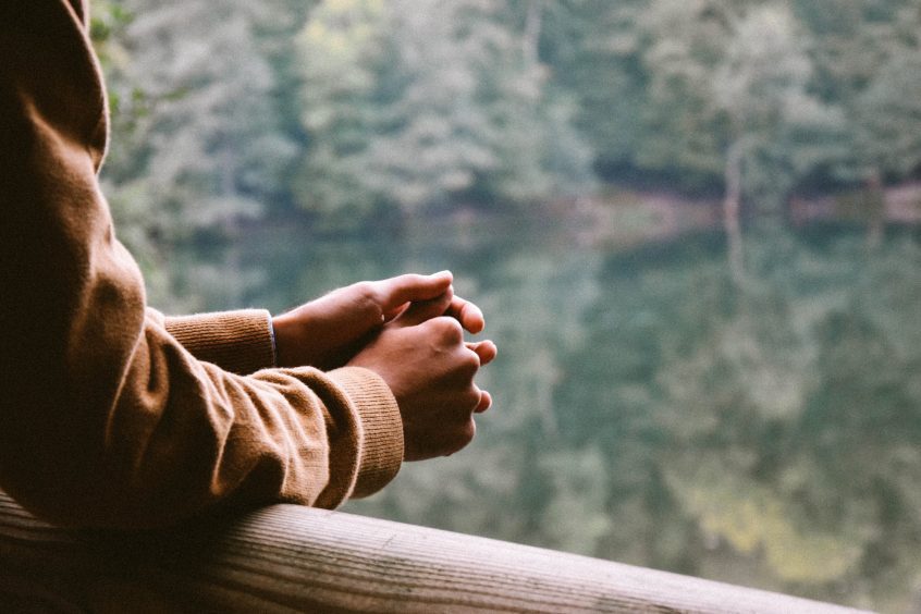 Man leaning on railing looking at a lake